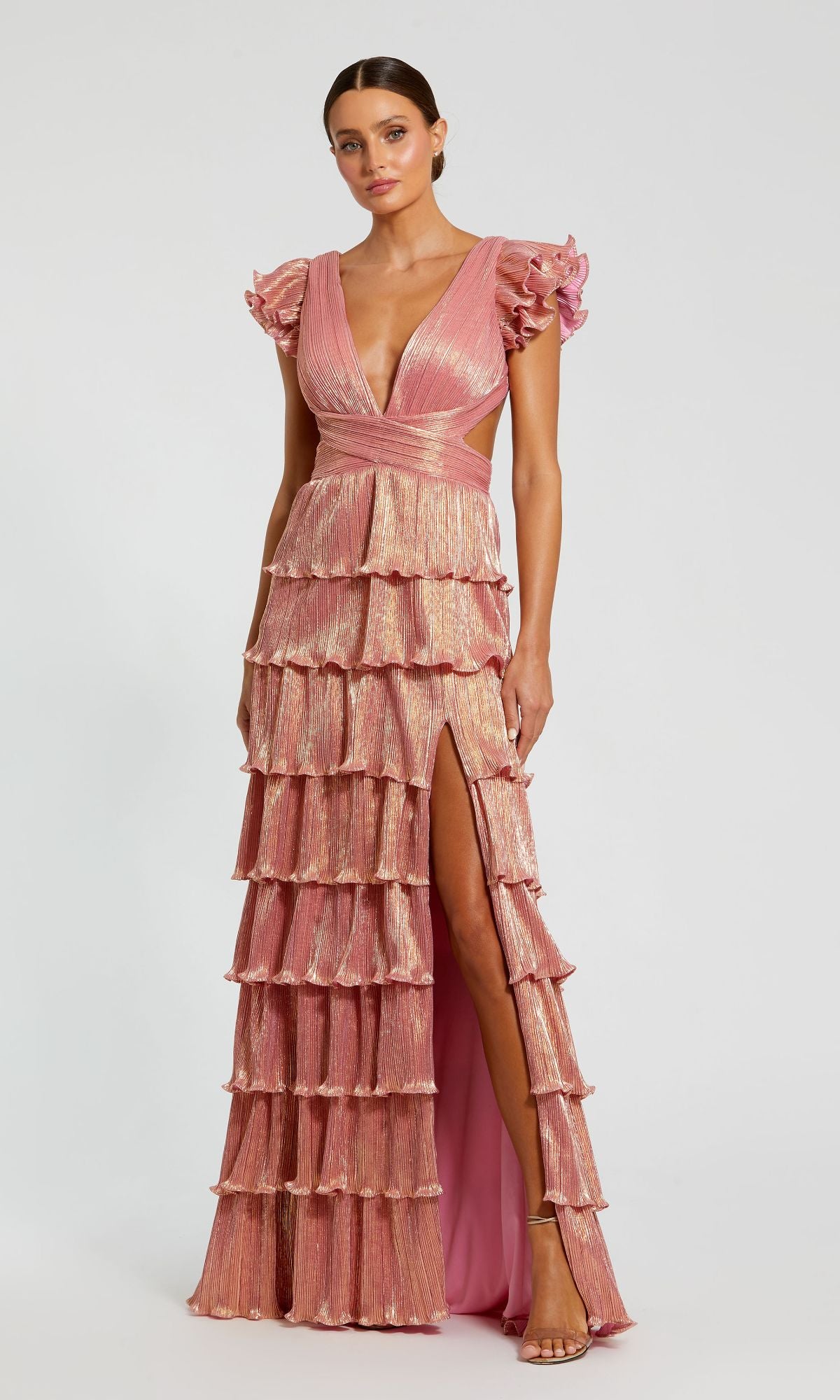A woman models the Mac Duggal Open-Back Tiered Formal Dress 26740 in pink, featuring a deep V-neckline, flutter sleeves, tiered ruffles, and a high slit, standing against a plain background.